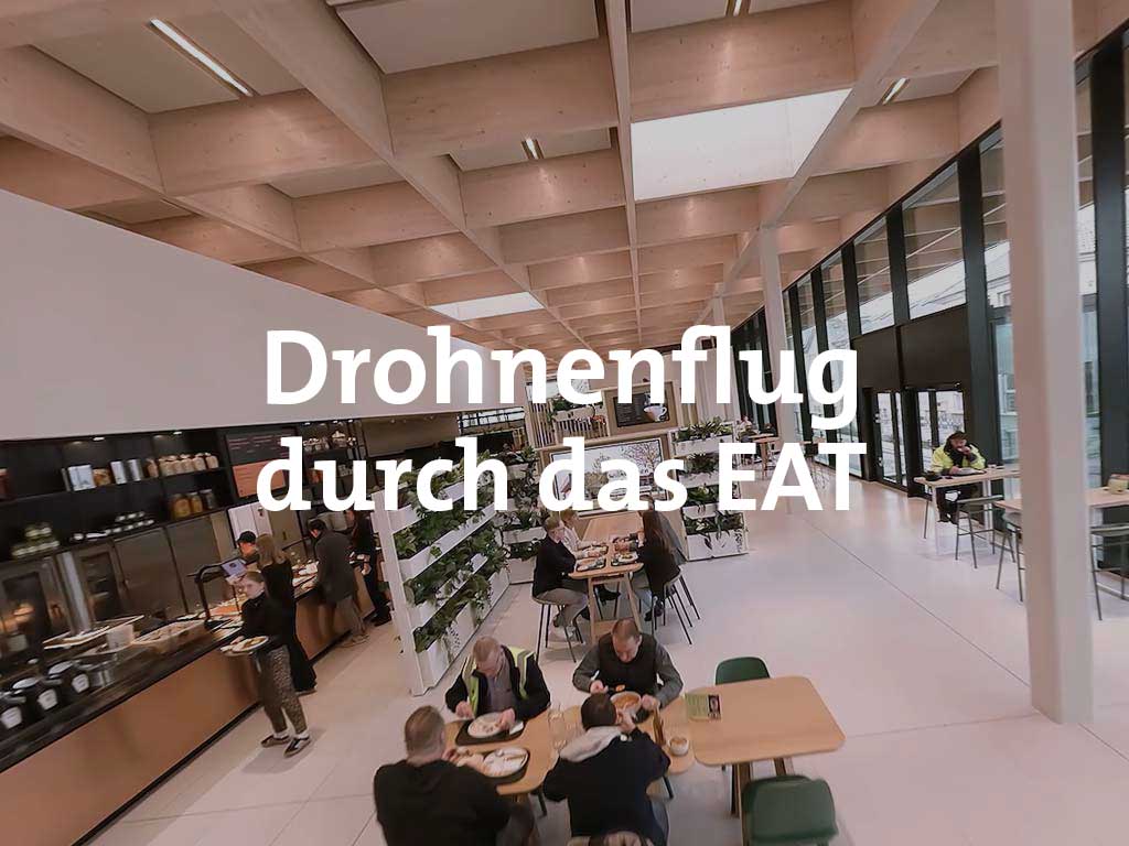 Drohnenaufnahme im EAT: Personen sitzen an Tischen und essen