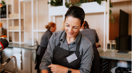 Mitarbeiterin steht hinter der 9bar und serviert